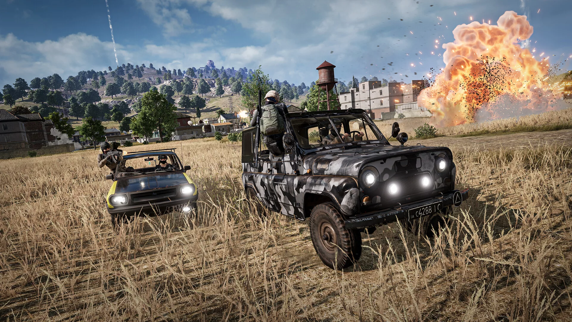 Jogadores em dois jipes num campo de trigo de PUBG: Battlegrounds, com uma explosão ao fundo